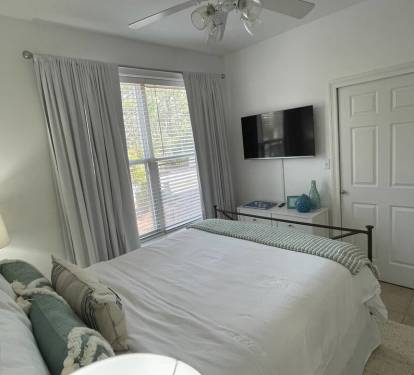 The large window overlooks the front yard, inviting natural light in while the wood blinds and room darkening drapes welcome peaceful sleep