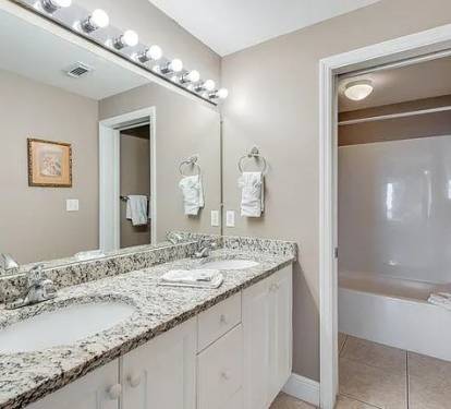 Wellâ€‘stocked master bathroom with dual sinks&mdash;bright, modern, and beachâ€‘inspired