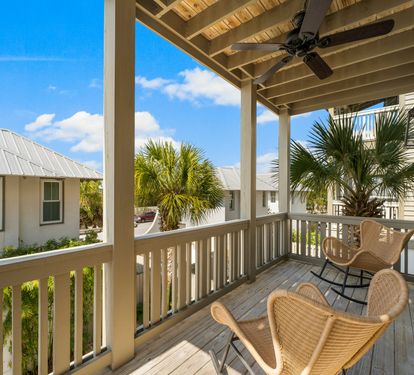 A breezy covered balcony with rocking chairs and palm-lined views &mdash; the perfect spot for morning coffee or an evening unwind