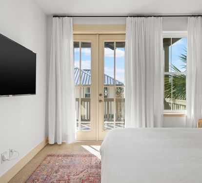 A serene king suite with French doors opening to the balcony &mdash; wake up to blue skies and palm views