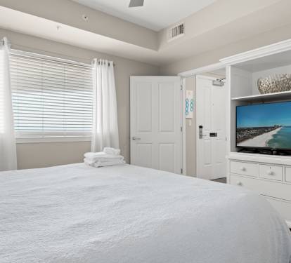 Bedroom w/ window light and TV, blending comfort and convenience.