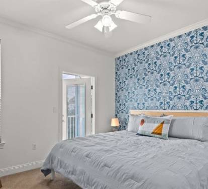 A king bed and whimsical seahorse wallpaper that says you're at the beach.