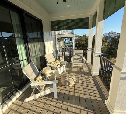Step straight from the upper master suite onto this covered porch — ceiling fan overhead, cushioned seating ready whenever the coastal breeze calls you outside."