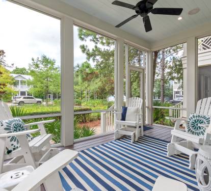 Screened porch w/ Adirondack chairs, ceiling fan & garden views for breezy outdoor lounging.