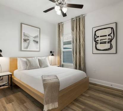 Bedroom 1: Elegant bedroom featuring a ceiling fan, natural light, and artistic touches