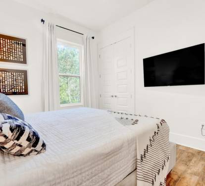 King bedroom on the main level with a 55" flat screen TV and a fan.  