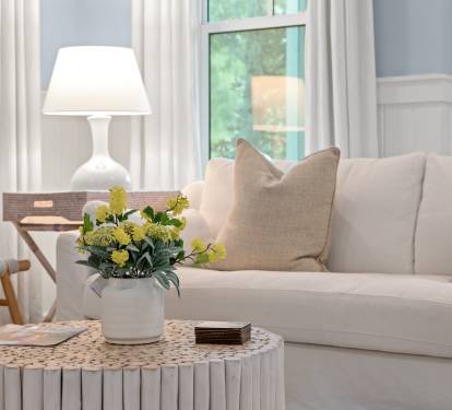 Cozy seating vignette w/ textured pillows, warm lamp glow & thoughtful decor accents.