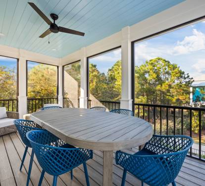 Screened upper porch dining just off the guest house kitchen, featuring a spacious table with coastal blue seating. This is the primary dining space for the home, overlooking the pool and perfect for shared meals, coffee, and relaxed evenings.