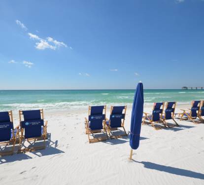 Sandy beach setup w/ chairs facing the water, made for long seaside days.