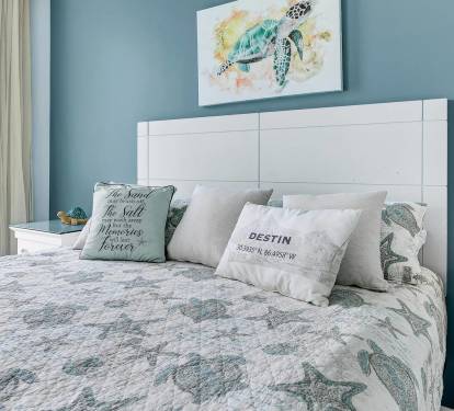 Close-up of the cozy bed w/ beachy decor details that set a relaxed vacation mood