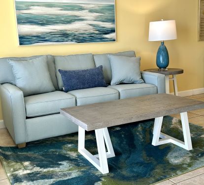 Family room with new sofa sleeper, art, carpet, tables. Designer furnished