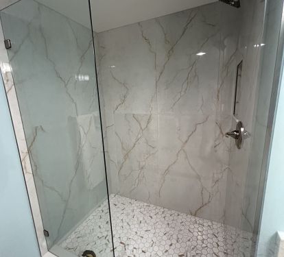 Newly updated walk-in custom tiled shower with seamless glass enclosure