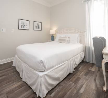 Cozy bedroom w/ a neatly made bed and soft natural light.
