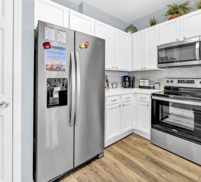 Another kitchen angle highlighting full-size fridge, modern appliances, & smart storage