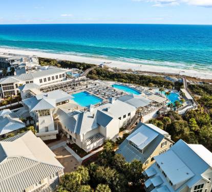 Aerial view of the community pools nestled near the shoreline, blending coastal scenery w/ relaxing amenities.