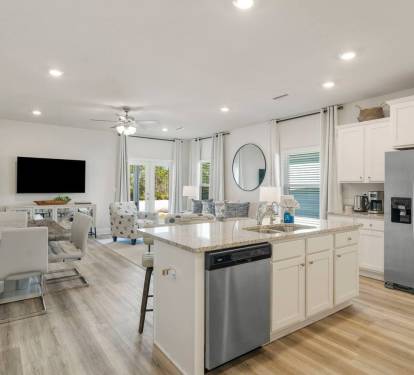 Main Kitchen: Stylish full kitchen with counter seating, stove, microwave, and open layout connecting dining and living area.