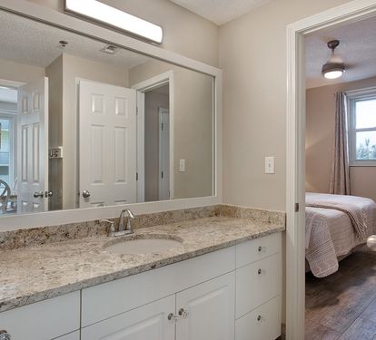 Guest bathroom with twin vanities and walk-shower accessible from living room