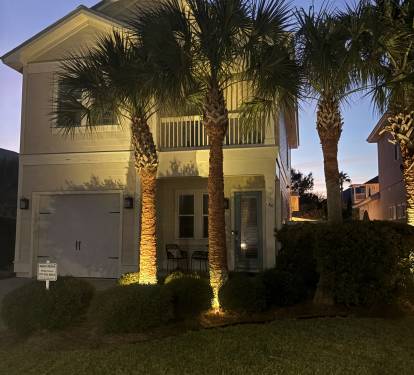 Evening exterior view highlighting the home’s coastal architecture and landscaping.