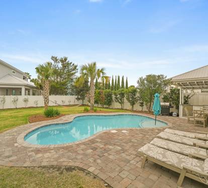 Daytime view of the private pool, patio, and landscaped backyard.