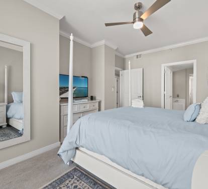 Primary bedroom w/ TV and simple coastal design for easy relaxation.