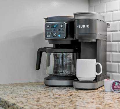 Coffee setup w/ Keurig, mugs & pods ready to jumpstart slow mornings.