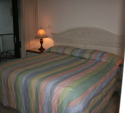 King bed in bedroom w/ patio door onto balcony