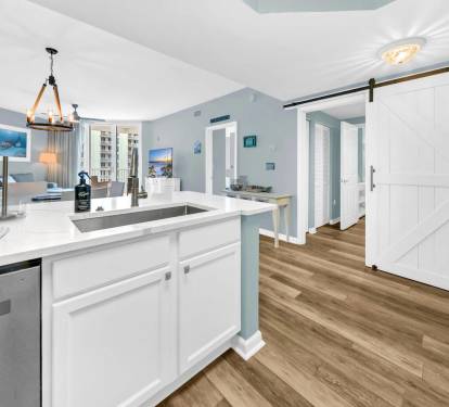 Open kitchen view flowing into the living space, w/ warm floors & a charming sliding barn door