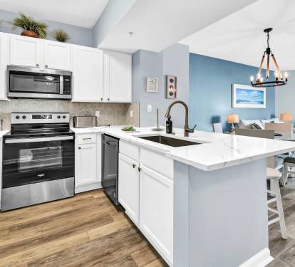 Modern kitchen w/ white cabinetry, island seating, & full-size appliances for easy meals