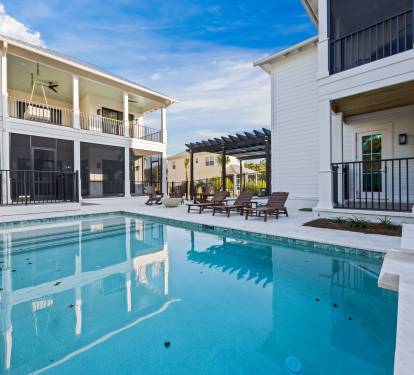 Private pool courtyard framed by both homes, with four porches surrounding the space, screened lower lounging areas, and direct outdoor staircase access from the upstairs bedrooms—designed for effortless indoor-outdoor living.