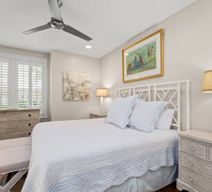 Calm bedroom retreat w/ plush bedding, ceiling fan & light-filled windows for restful nights.