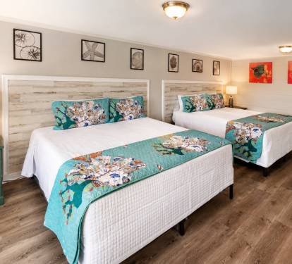 A Double King Suite features a private exterior entry door and two king-size beds.  Two dressers and a smart TV