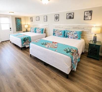 A Double King Suite features a private exterior entry door and two king-size beds.  Two dressers and a smart TV