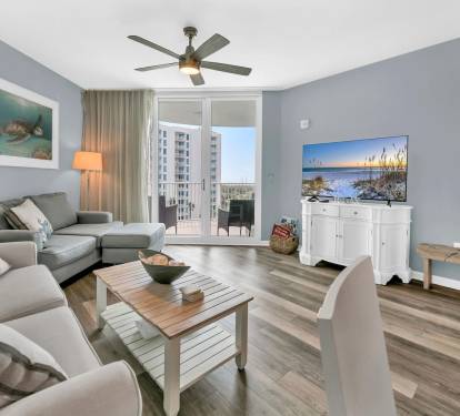 Bright coastal living room w/ comfy seating, smart TV, & sliding doors opening to the balcony