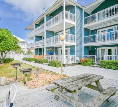 The outdoor area perfect for an afternoon picnic. In the foreground, a charcoal grill and a wooden picnic table off of a grassy area. The condo is the corner patio unit. Kids can easily play in the grass, while your enjoying a drink on the patio. 