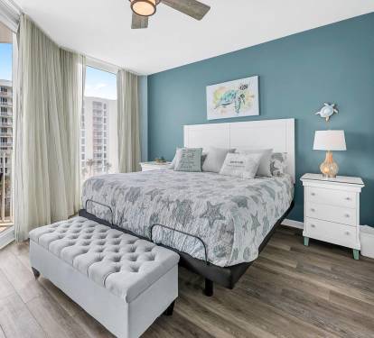 Serene bedroom w/ plush bed, ocean-inspired decor, & floor-to-ceiling windows for natural light