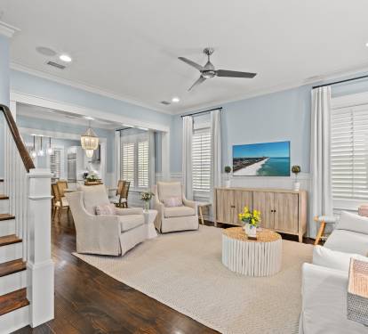 Inviting living area w/ soft blue walls, plush chairs & natural light from tall windows.