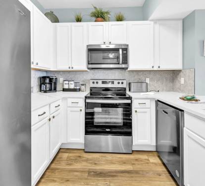 Bright, full kitchen w/ stainless appliances, ample counter space, & clean white cabinetry