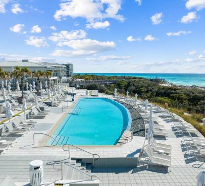 Resort-style pool surrounded by loungers & umbrellas, perfect for sunny afternoons near the water.