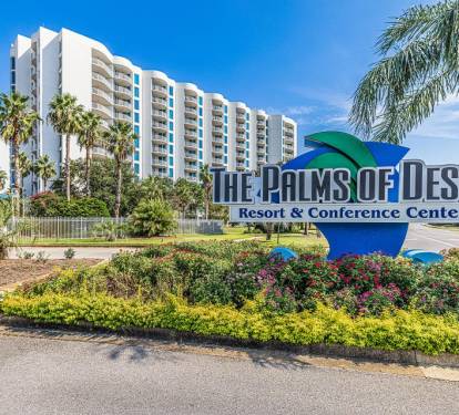 Exterior view of the condo buildings surrounded by palm trees and walkable paths.
