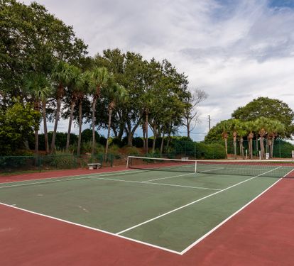 Community tennis court surrounded by lush greenery