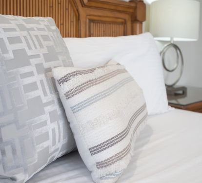 Crisp bed styled w/ layered pillows and soft textures for a restful night’s sleep.