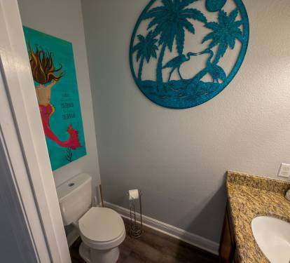 Bright beach-inspired décor and playful coastal touches bring personality and charm to the hallway half bath.