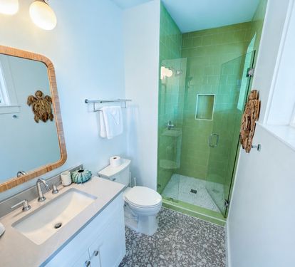 Ensuite Bathroom 6 features a generous vanity and a walk-in shower accented by soft green tile, blending refined finishes with a refreshing touch.