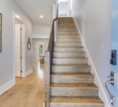 Bright entryway featuring hardwood floors and a modern staircase leading to the upper level.