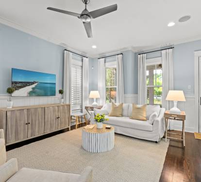 Bright living room w/ soft blue walls, comfy seating & large windows that fill the space w/ natural light.