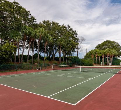 Community tennis court surrounded by lush greenery