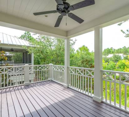 Covered balcony w/ ceiling fan & peaceful treetop views, ideal for morning coffee or evening downtime.