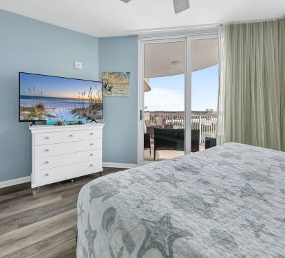Relaxing bedroom retreat w/ TV, soft coastal colors, & direct access to the balcony