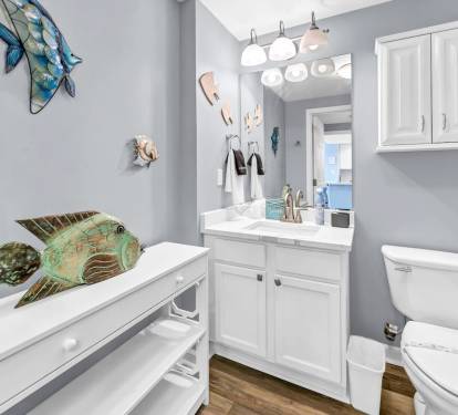Clean coastal bathroom w/ white vanity, bright lighting, & beachy accents for a fresh start to the day