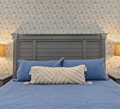 A king bed retreat with coastal wallpaper and soft blue tones